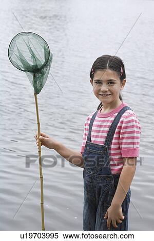Stock Photography - Girl (5-6) with fishing net by water, portrait. Fotosearch