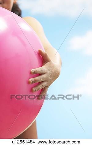 Girl (7-9 years) holding ball on beach, close up of ball View Large Photo Image Picture - Girl (7-9 years) holding ball on beach, close up of ball. Fotosearch