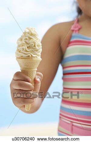 Stock Image - Girl (7-9 years) holding icecream, mid section. Fotosearch