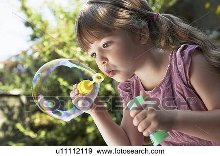 Girl Blowing Soap Bubbles in backyard, close up View Large Photo Image Stock Photo - Girl Blowing Soap Bubbles in backyard, close up. Fotosearch