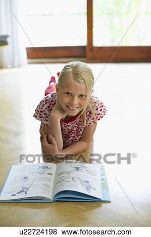Girl lying on floor at home reading book, portrait View Large Photo Image Stock Photo - Girl lying on floor at home reading book, portrait. Fotosearch