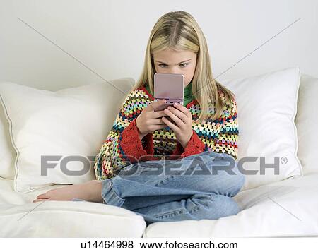 Girl sitting, barefoot on sofa, Playing Handheld Video Game View Large Photo Image Stock Photo - Girl sitting, barefoot on sofa, Playing Handheld Video Game. Fotosearch