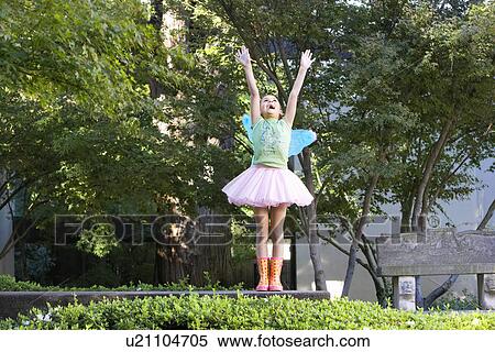 Stock Photography - Girl wearing tutu and fairy wings playing in park. Fotosearch