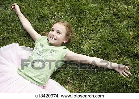 Girl wearing tutu lying on grass, view from above View Large Photo Image Picture - Girl wearing tutu lying on grass, view from above. Fotosearch