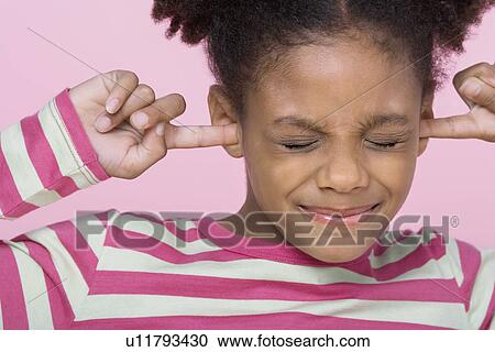 Stock Image - Girl with eyes closed, putting Fingers in Ears, close-up. Fotosearch
