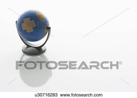 Stock Image - Globe with two pieces of sticking plaster on it. Fotosearch