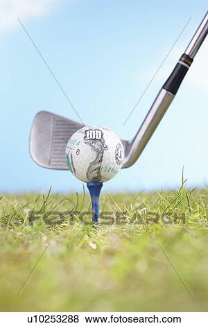 Golf club hitting golf ball with hundred-dollar logo on tee, close-up View Large Photo Image Stock Photo - Golf club hitting golf ball with hundred-dollar logo on tee, close-up. Fotosearch