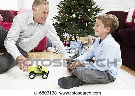 Grandfather playing with grandson on floor by christmas tree View Large Photo Image Stock Photo - Grandfather playing with grandson on floor by christmas tree. Fotosearch