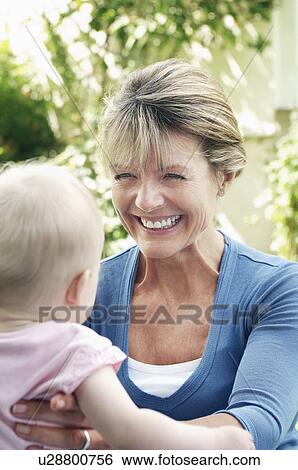 Stock Photograph - Grandmother and granddaughter in garden, head and shoulders. Fotosearch