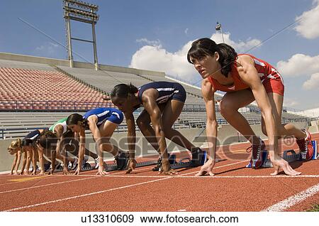 Stock Photo - Group of female track athletes on starting blocks. Fotosearch