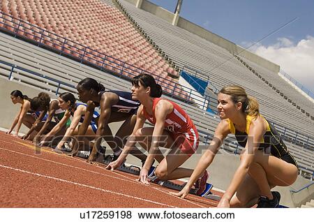 Stock Photo - Group of female track athletes on starting blocks. Fotosearch