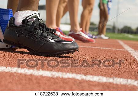 Stock Photo - Group of female track athletes on starting blocks. Fotosearch