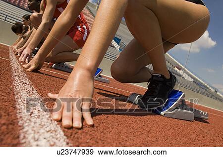 Stock Photo - Group of female track athletes on starting blocks. Fotosearch