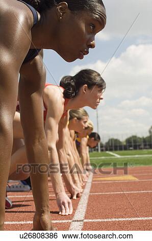 Stock Photograph - Group of female track athletes on starting blocks. Fotosearch