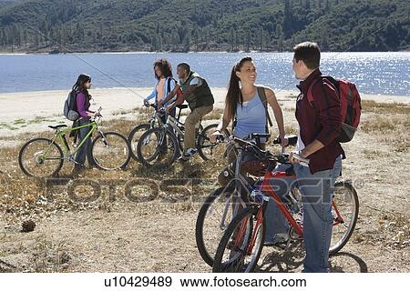 Group of fiends stand at lakeside with mountain bikes View Large Photo Image Stock Photo - Group of fiends stand at lakeside with mountain bikes. Fotosearch
