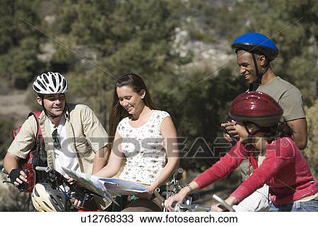 Stock Image - Group of friends looking at map on cycling holiday. Fotosearch
