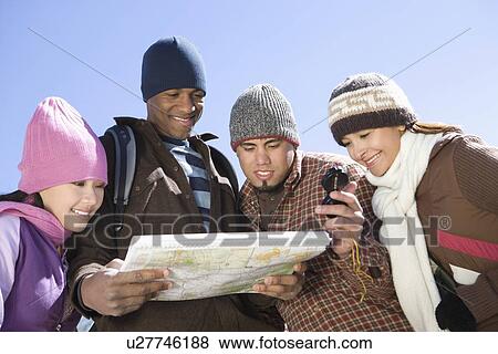 Stock Photo - Group of friends stand looking at map together. Fotosearch