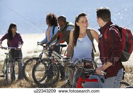 Group of young adults standing by lake with mountain bikes. View Large Photo Image Stock Photo - Group of young adults standing by lake with mountain bikes.. Fotosearch