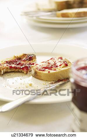 Half-eaten toast with jam on plate with butter knife, close-up View Large Photo Image Stock Photo - Half-eaten toast with jam on plate with butter knife, close-up. Fotosearch