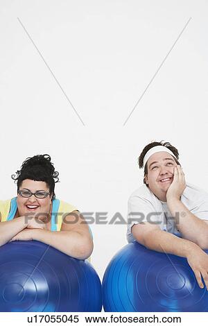 Stock Photography - Happy overweight man and woman Resting on Exercise Balls, front view. Fotosearch