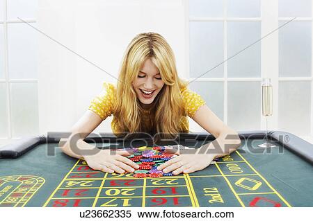 Stock Photography - Happy woman at roulette table collecting chips. Fotosearch