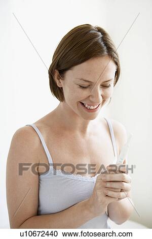 Happy woman looking at pregnancy test smiling View Large Photo Image Stock Image - Happy woman looking at pregnancy test smiling. Fotosearch