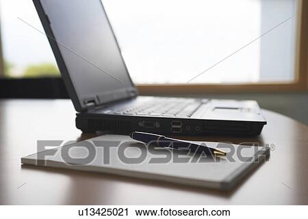 Stock Image - Laptop and notepad on desk. Fotosearch