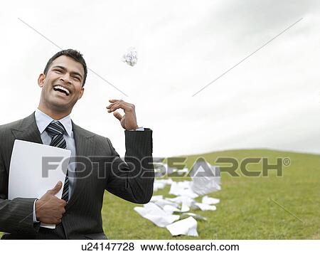 Laughing business man on grass field throwing litter behind View Large Photo Image Stock Photo - Laughing business man on grass field throwing litter behind. Fotosearch