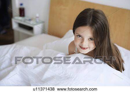 Stock Photo - Little girl sitting up in bed, portrait. Fotosearch