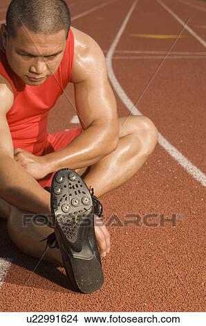 Picture - Male athlete stretching on track. Fotosearch