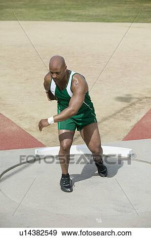 Stock Photo - Male athlete training with discus in circle. Fotosearch