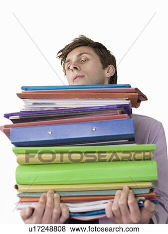 Stock Photo - Male office worker carrying heavy binders, close-up. Fotosearch