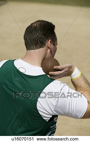 Stock Image - Male shot putter holding shot. Fotosearch