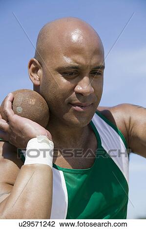 Stock Image - Male shot putter holding shot. Fotosearch