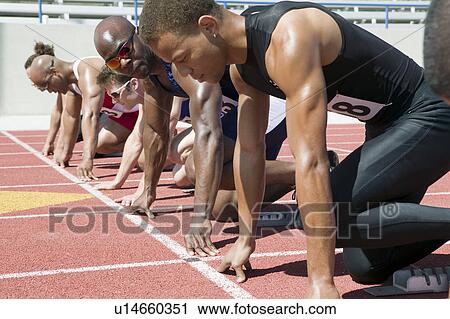 Stock Image - Male sprinters in starting blocks. Fotosearch