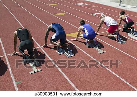 Stock Image - Male sprinters in starting blocks. Fotosearch