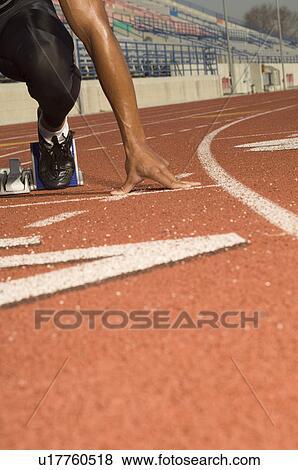 Stock Photo - Male track athlete on starting block. Fotosearch