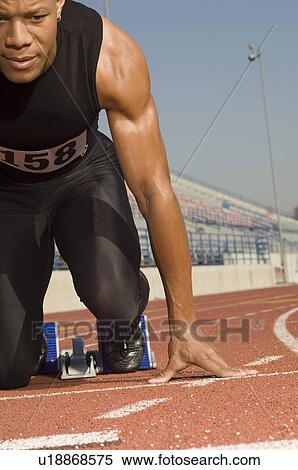 Stock Photography - Male track athlete on starting block. Fotosearch