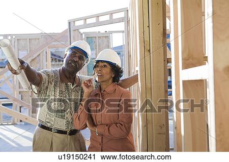 Stock Image - Man and woman at construction site, talking. Fotosearch