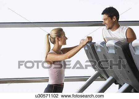 Stock Image - Man and Woman Talking by treadmill in Health Club. Fotosearch