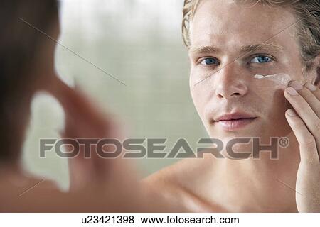 Man applying facial cream in front of mirror View Large Photo Image Stock Photo - Man applying facial cream in front of mirror. Fotosearch
