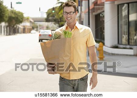 Stock Photograph - Man carrying groceries after shopping, portrait. Fotosearch