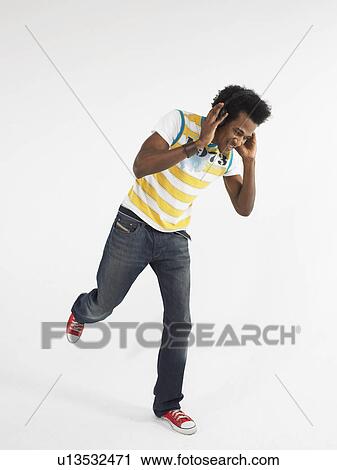 Stock Image - Man dancing while wearing headphones in studio. Fotosearch