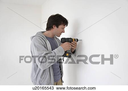 Man drilling hole in wall View Large Photo Image Stock Image - Man drilling hole in wall. Fotosearch