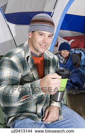 Picture - Man drinking in front of tent. Fotosearch