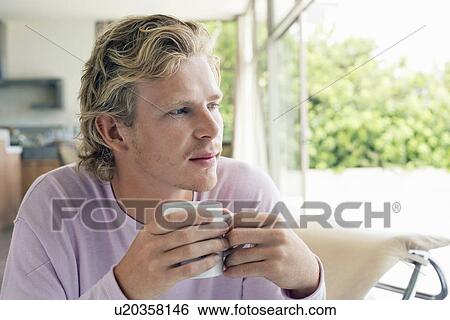 Stock Photograph - Man having coffee in living room. Fotosearch