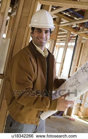 Man holding blueprint in construction site View Large Photo Image Stock Photograph - Man holding blueprint in construction site. Fotosearch