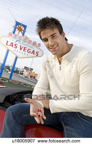 Man holding dice, Las Vegas 'welcome' sign in background View Large Photo Image Stock Photo - Man holding dice, Las Vegas 'welcome' sign in background . Fotosearch