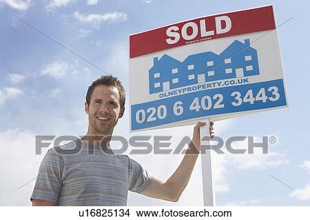 Man holding sold sign, against sky View Large Photo Image Picture - Man holding sold sign, against sky. Fotosearch