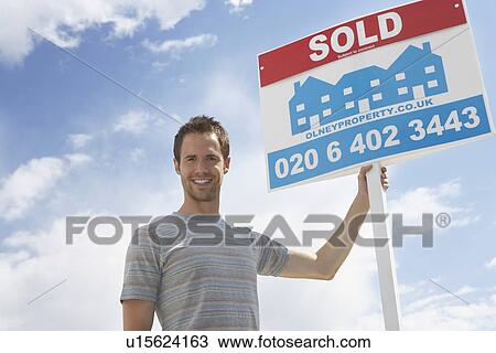 Man holding sold sign, against sky View Large Photo Image Stock Image - Man holding sold sign, against sky. Fotosearch